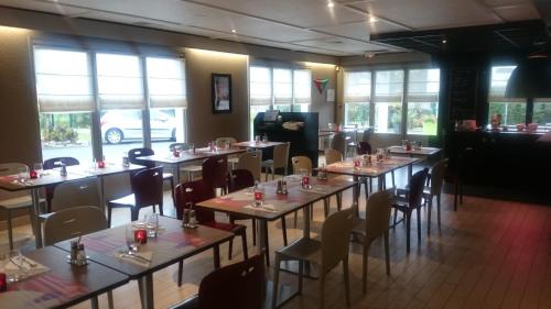 une salle à manger avec tables, chaises et fenêtres dans l'établissement Campanile Bayonne, à Bayonne