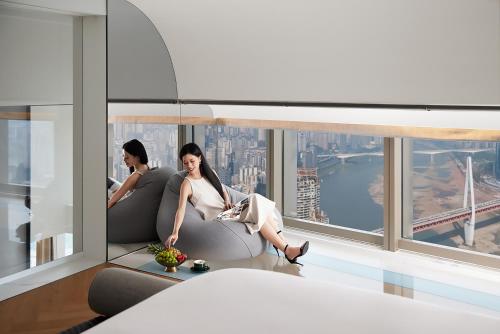 two women sitting on chairs in a room with a window at ISEYA Panoramic Hotel Chongqing Jiefangbei Raffles Plaza in Chongqing