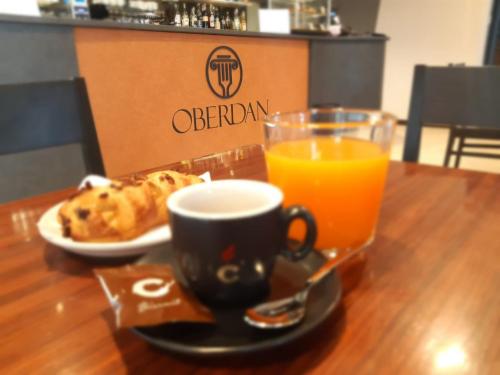 a table with a cup of orange juice and a plate of food at Hotel Oberdan Ristorante Pizzeria in Concordia Sagittaria