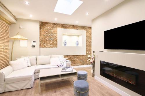 a living room with a white couch and a fireplace at El capricho II en la Plaza Mayor centro Salamanca by keyhom in Salamanca