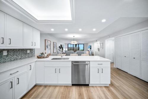 Una cocina con gabinetes blancos y lavavajillas de acero inoxidable. en Pine Cove #102, en Sanibel