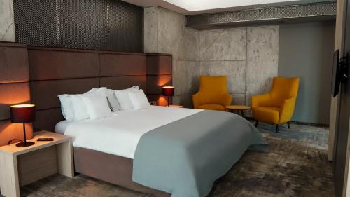 a bedroom with a large white bed and two chairs at Aniroc Signature Hotel in Arad