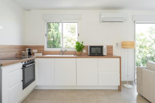 a kitchen with white cabinets and a sink and a window at Villa Mimosa in Marignane