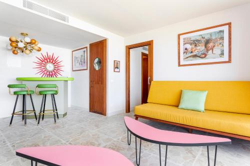 a living room with a yellow couch and stools at Los Felices Ibiza in San Antonio Bay