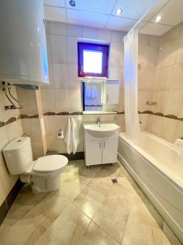 a bathroom with a toilet and a sink and a window at Long Sunny Holiday in Shkorpilovtsi