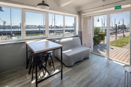 a room with a table and a couch and windows at Smiltynės Jachtklubas in Klaipėda