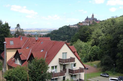 a house on a hill with a castle in the background at REGIOHOTEL Schanzenhaus Wernigerode in Wernigerode