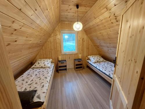 an attic room with two beds and a window at Kaszubskie Domki Nad Jeziorem Bluj in Głodowo