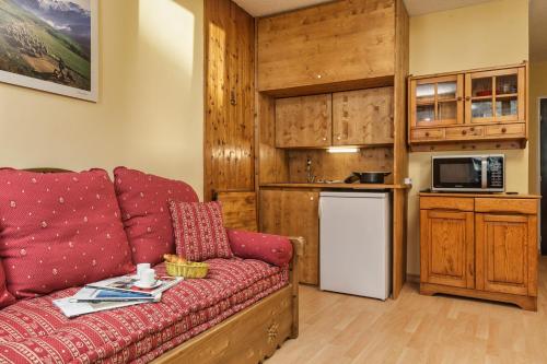 un salon avec un canapé rouge et une cuisine dans l'établissement Chamonix Sud - Bâtiment G 45 - Happy Rentals, à Chamonix-Mont-Blanc