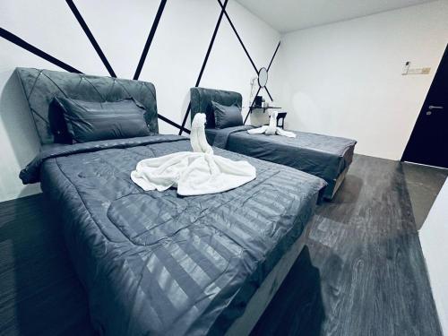 a bedroom with two beds with a swan on it at Kuu Inn Hotel in Arau