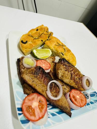 a plate of food with fish and bread and tomatoes at The Sunset Villa in Dhiffushi