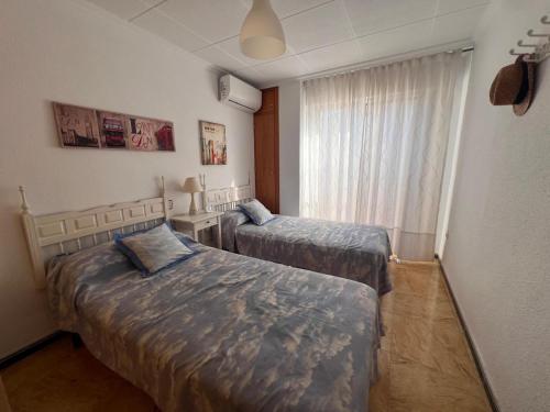 two beds in a small room with a window at Impecable piso a 300 mt del mar! in Puerto de Mazarrón