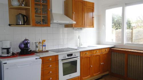 une cuisine avec des armoires en bois et un four blanc dans l'établissement gite de mer familial, plage et commerces à pied, à Grandcamp-Maisy