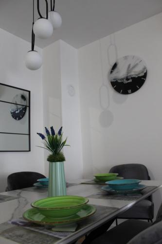 a dining room table with green plates and a vase at Apartman Nivalis in Čapljina