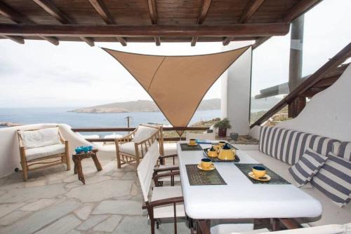 um pátio com uma mesa e cadeiras e o oceano em Apt with Amazing Balcony View of Mykonos em Agios Sostis Mykonos