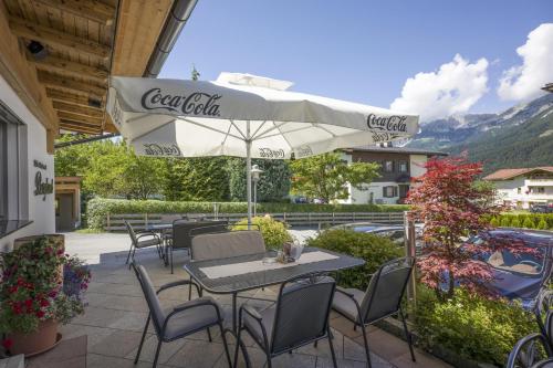 a patio with tables and chairs and an umbrella at Appartements Bergland in Ellmau
