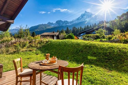 una mesa y sillas en una terraza con vistas a las montañas en Chalet des Cristaux Happy Rentals, en Chamonix-Mont-Blanc