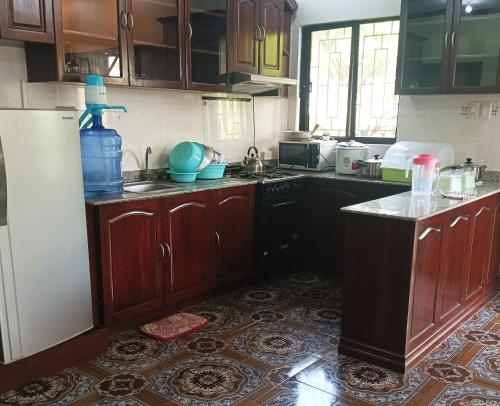 a kitchen with wooden cabinets and a sink and a refrigerator at Sunrise Guesthouse and Inn, Panglao in Panglao