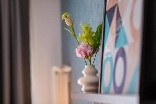 a vase with flowers in it sitting on a shelf at Urban Elegance - Stylish Central Accommodation in Bucharest