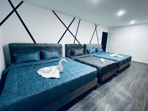 two beds in a room with two swans on them at Kuu Inn Hotel in Arau