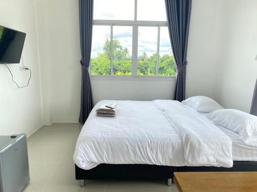 a bedroom with a large bed with a window at Dino Homestay in Ban Muang Chum