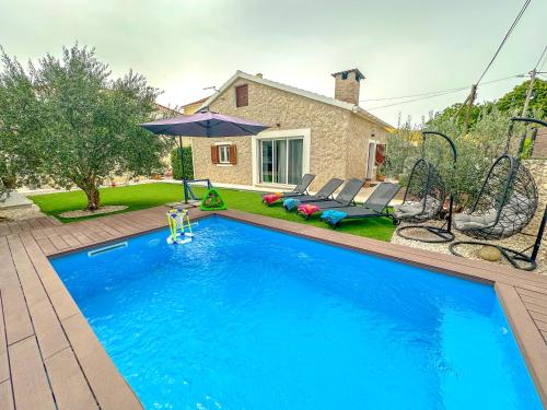 a swimming pool with two chairs and an umbrella at MUSTRA House Zadar - Private Pool & Sauna in Zadar