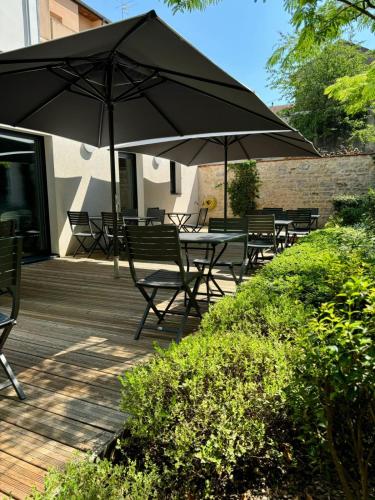 a deck with tables and chairs and an umbrella at Hôtel des Halles in Dijon