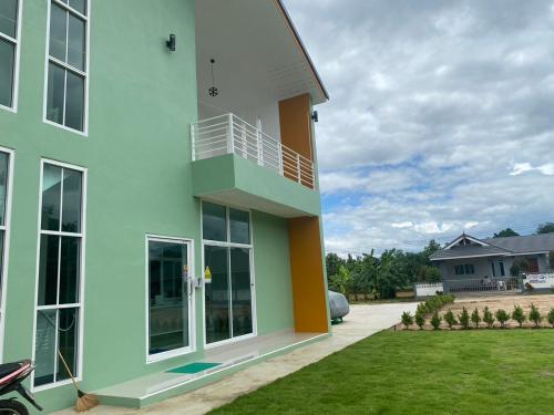 a building with a balcony on the side of it at Dino Homestay in Ban Muang Chum