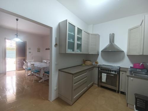 uma cozinha com armários brancos, uma mesa e uma sala de jantar em Sunset Villa em Torre Lapillo