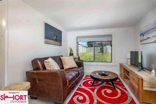 a living room with a couch and a television at Bright, Cosy Cottage near CBD- Free wifi, Netflix and Disney Plus in Orange