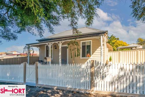 a small house with a white picket fence at Bright, Cosy Cottage near CBD- Free wifi, Netflix and Disney Plus in Orange