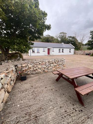 a picnic table in front of a stone wall and a building at Mia's Self Catering Holiday Cottage Donegal in Claggan