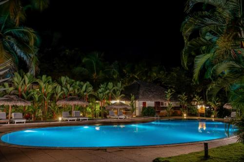a swimming pool at night with palm trees at Malabar Ocean Front Resort And Spa, Bekal in Nīleshwar