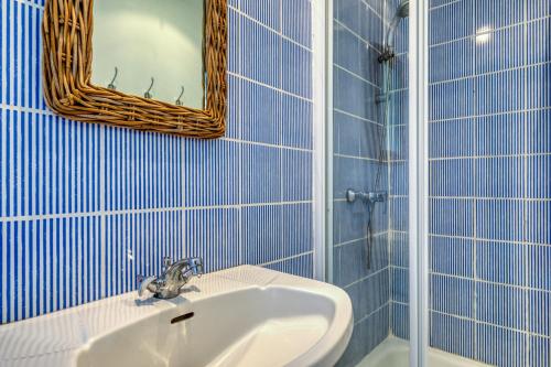 a blue tiled bathroom with a sink and a mirror at Mas des Cypres - Mazet 7 in Saintes-Maries-de-la-Mer