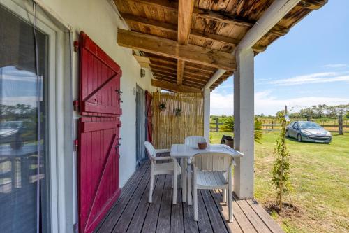 a porch with a table and chairs and a red door at Mas des Cypres - Mazet 7 in Saintes-Maries-de-la-Mer