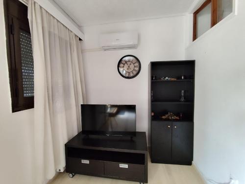 a living room with a tv and a clock on the wall at Ευρύχωρο και άνετο διαμέρισμα στην Ιτέα Joanna's Apartment in Kírra