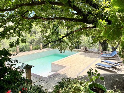 une piscine avec deux chaises longues à côté dans l'établissement Bastide provençale familiale, grande piscine, prés d'Aix en pleine nature, à Bouc-Bel-Air