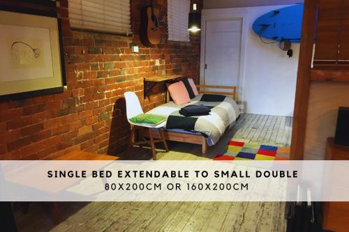 Edithvaleにあるbeachside loft warehouse artists retreatのベッドと椅子のある小さな寝室