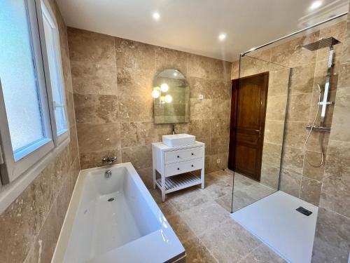 une salle de bain avec baignoire et douche en verre dans l'établissement Bastide provençale familiale, grande piscine, prés d'Aix en pleine nature, à Bouc-Bel-Air