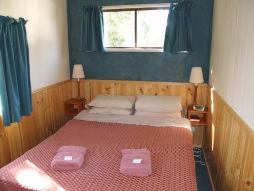 a bedroom with a bed with two pink towels on it at Launceston Holiday Park Legana in Legana