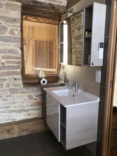 une salle de bain avec un lavabo et un mur en pierre dans l'établissement Maison Millot, à Beaune