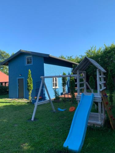 a playground in front of a house with a slide at Domek letniskowy Kopalino nad morzem in Lubiatowo