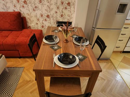 a wooden table with plates and glasses on it in a kitchen at - All-Around Skopje Apartments - Premium Hospitality - in Skopje