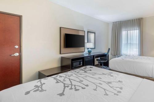 a hotel room with two beds and a desk with a television at Sleep Inn & Suites Norman near University in Norman