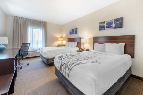 a hotel room with two beds and a desk at Sleep Inn & Suites Norman near University in Norman