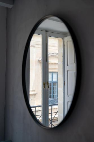 a round mirror in a room with a window at The Republic Boutique Hotel in Valletta
