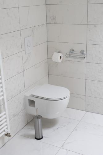 a bathroom with a toilet in a white tiled wall at Apartmani Link in Požega