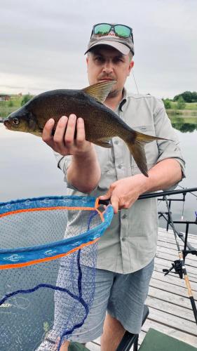 a man holding a fish on a boat at Pineplace twins NIDA in Žaugėdai