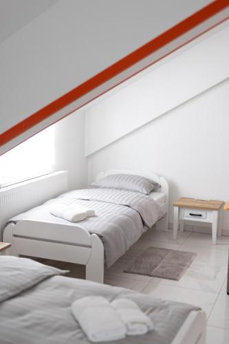 a white bedroom with two beds and a table at Apartmani Link in Požega