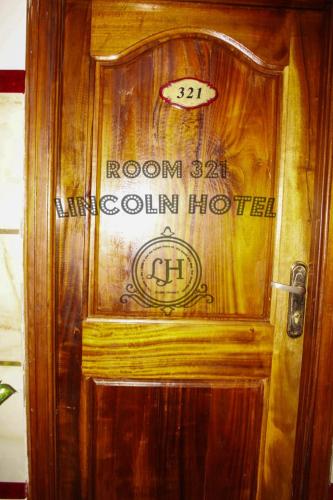 a wooden door with a sign on it at Lincoln Prestige Hotel in Accra